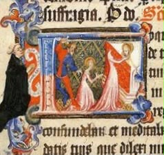 A detail from a medieval illuminated manuscript showing the martyrdom of St Juthware. Inside a decorated initial letter, the saint kneels in prayer wearing a white gown, her hands raised, while a man in a red tunic and hood stands over her with a raised sword, about to strike. To the right, a haloed figure in golden robes looks on. The scene is set against a patterned green and gold background. The initial is framed in pink and blue, surrounded by lines of black Latin text in Gothic script, with ornate blue, red and gold flourishes curling down the left margin, where a small monk in dark robes stands watching. The colours are rich despite the manuscript's age, with gold leaf details still catching the light.