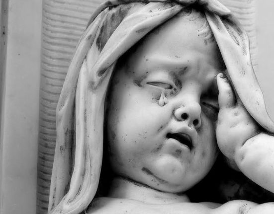 Black and white photograph of a stone sculpture showing a veiled face in profile, carved religious monument detail from Jim Johnson's Dorset churches photography project"