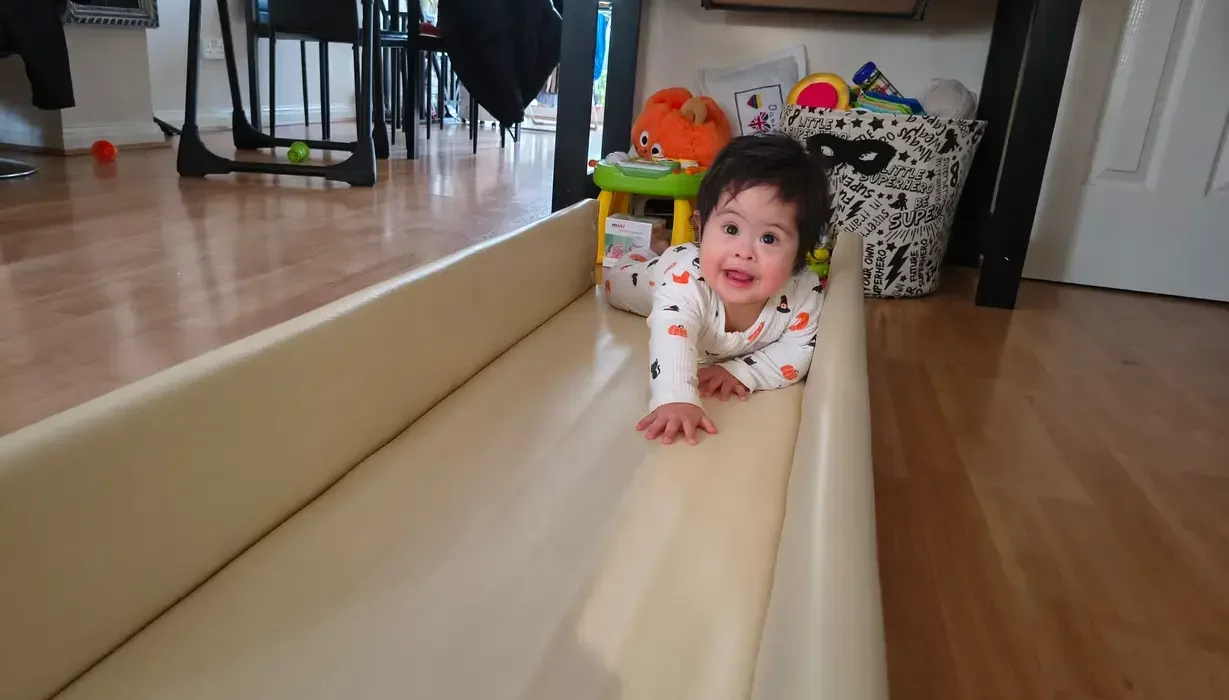 Baby Daniel, who has Down's Syndrome, crawling along tracks built as part of REMAP's disabled adaptations to help disabled children with mobility at home