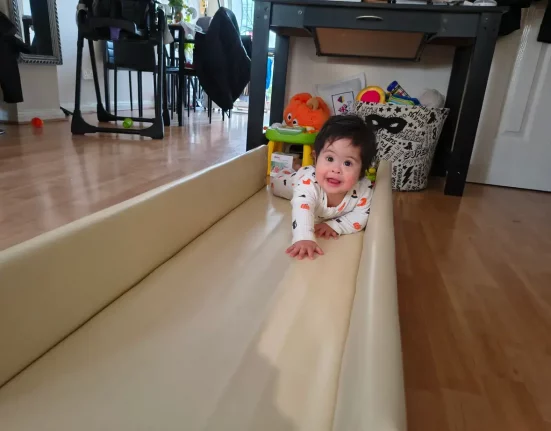 Baby Daniel, who has Down's Syndrome, crawling along tracks built as part of REMAP's disabled adaptations to help disabled children with mobility at home