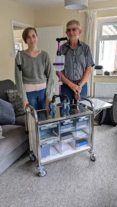 Hollie with a REMAP volunteer engineer beside the custom pump stand and trolley made as part of her disabled adaptations