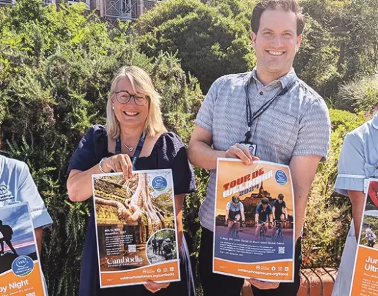 Weldmar Hospicecare staff hold posters for the four new 2027 fundraising challenges - Snowdon by Night, Cambodia Overseas Challenge, Tour de Weldmar and Jurassic Coast Ultra Challenge - outside the hospice in Dorchester
