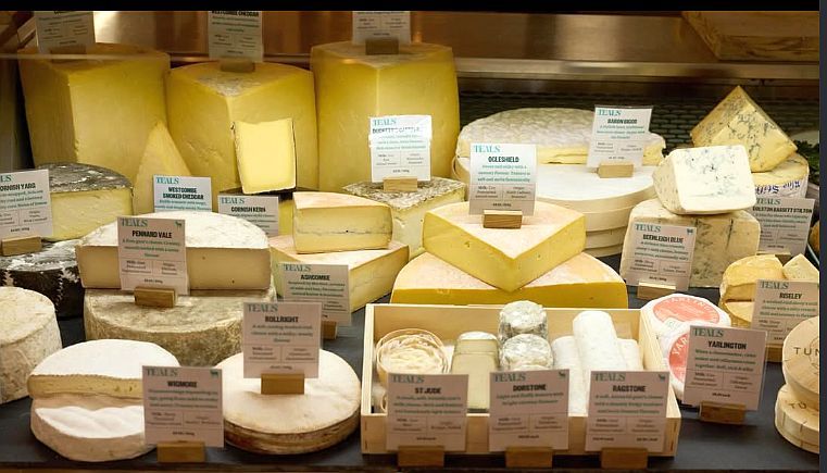 The cheese counter at Teals Farm Shop, with a wide selection of British cheeses including Westcombe Smoked Cheddar, Ogleshield, Pennard Vale, Beenleigh Blue, Wigmore, St Jude, Dorstone and Ragstone, each with a handwritten Teals label.