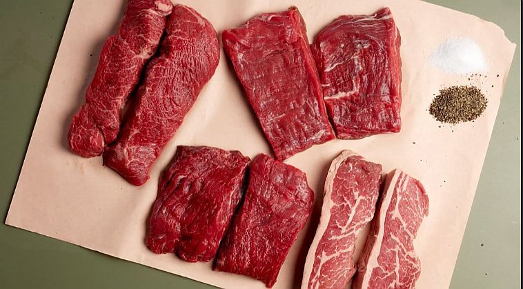 Pairs of raw beef steaks in a range of cuts laid out on butcher’s paper with small piles of salt and black pepper, from the butchery counter at Teals Farm Shop.
