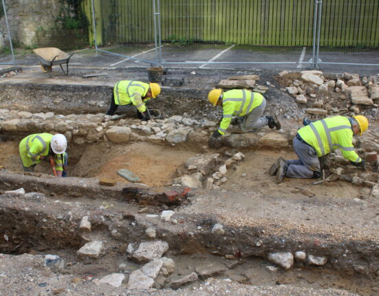 Dorset archaeology: volunteers in hi-vis jackets and hard hats excavate stone wall foundations at the North Quay site in Weymouth, during the dig led by Context One Heritage and Archaeology for Dorset Council.