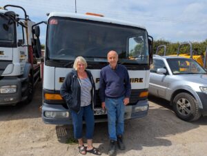 Graham Evans, 82, and wife Pauline, working past retirement age, stand in front of an Evans Plant Hire lorry at their yard.