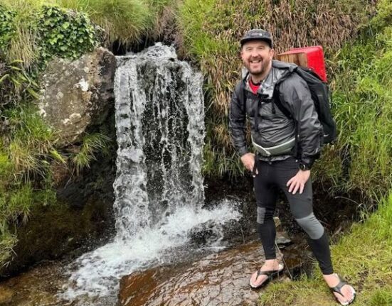 Weymouth man carries postbox 650 miles for Head Outside charity: Stu Skinner MBE smiles beside a waterfall with the red postbox strapped to his backpack